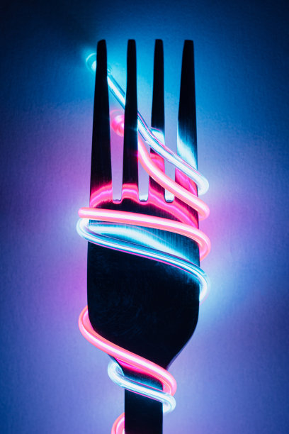 叉子与霓虹灯led电缆意大利面在黑暗的背景。图片下载