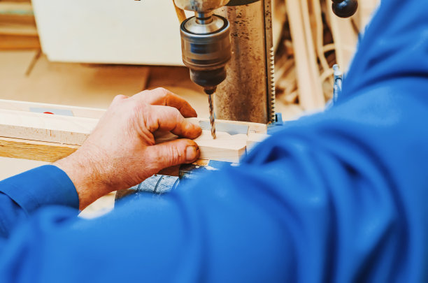 在木板上钻孔。制作画架的木腿。细木工的工作。近距离观察大师的手。图片下载