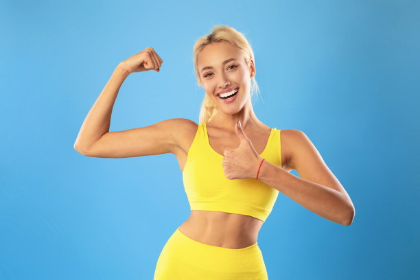 快乐的运动女人显示强壮的二头肌和大拇指图片下载