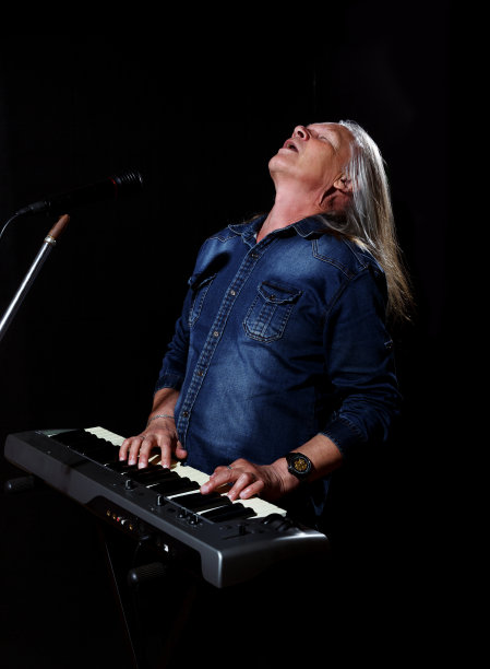 一位长着灰色长发的老人在弹奏琴键图片下载