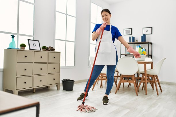 年轻的中国家庭主妇微笑着在家里用拖把洗地板。图片下载
