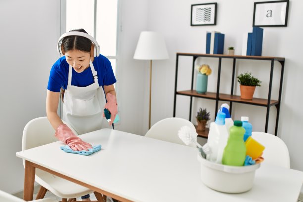 年轻的中国家庭主妇在家用耳机打扫卫生和听音乐。图片下载