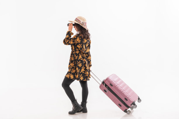 年轻女子提着箱子走着，透过望远镜看向别处图片下载