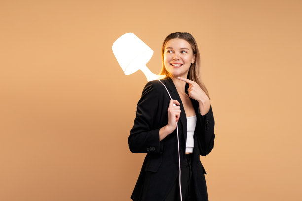 创造力和创新精神是成功的关键。以灯光照明的新理念和创新理念。美丽微笑的白种人女人手里拿着灯，微笑孤立。图片下载