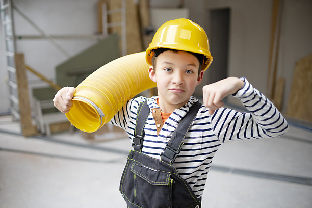 工地上戴黄色安全帽、管黄色管子的酷小子图片下载