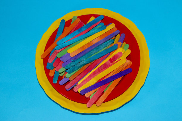 一个黄色的盘子，一个红色的小盘子，上面有很多彩色的小棒，这是一个很漂亮的构图图片下载