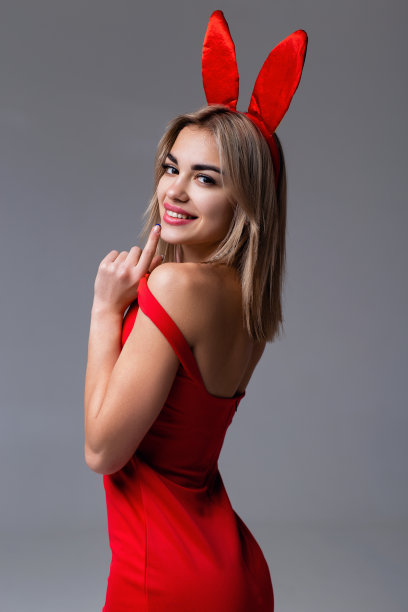 一个美丽的微笑女孩的工作室肖像，穿着红色的裙子和兔子耳朵。图片下载