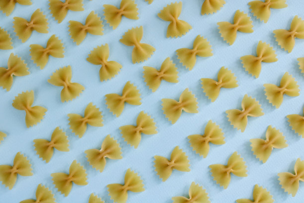 意大利面farfalle图案在蓝色的背景上。生farfalle意大利面在彩色背景图片下载