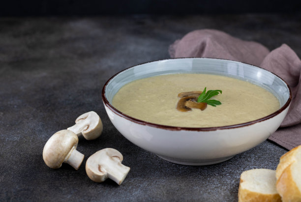 蘑菇汤与丝滑的质地在碗与土司在黑暗的背景，侧视图。有选择性的重点。图片下载