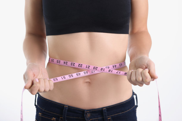 一个女人用一根模糊的带子量她的腰围图片下载