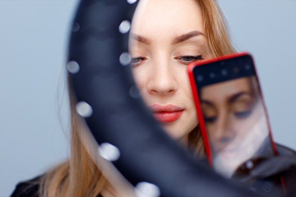 美容师用手机拍摄年轻女性嘴唇上的红色永久化妆纹身作品图片下载