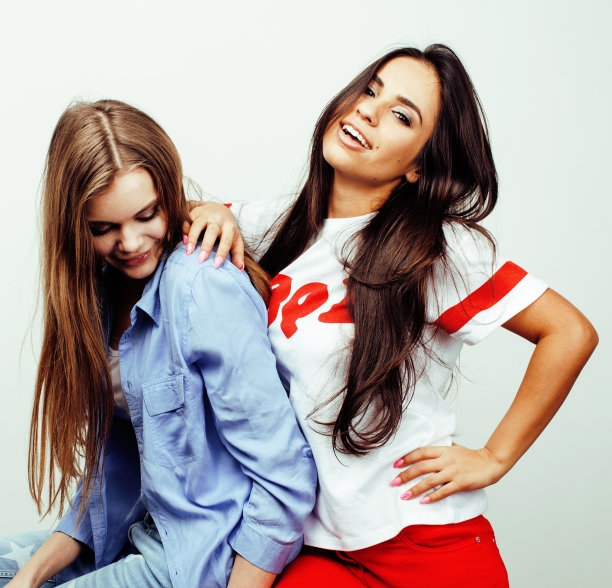 最好的朋友十几岁的女孩在一起有乐趣，在白色的背景下摆出情绪，最好的朋友快乐的微笑，生活方式的人的概念，金发和黑发的多国接近图片下载