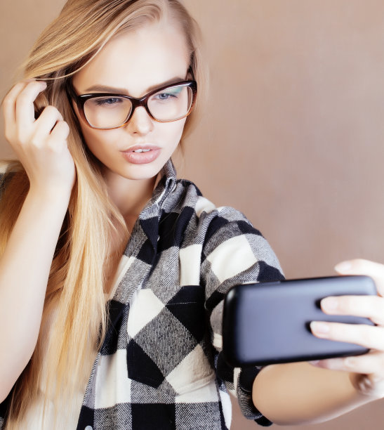 年轻漂亮的女孩十几岁，戴着眼镜在学校自拍，背着背包的学生，生活方式和人的概念图片下载