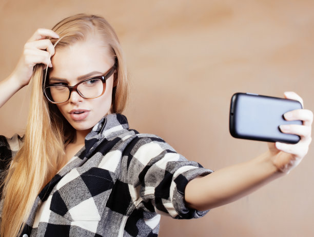 年轻漂亮的女孩十几岁，戴着眼镜在学校自拍，背着背包的学生，生活方式和人的概念图片下载