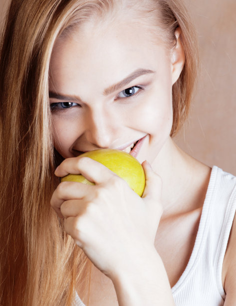 年轻漂亮的金发女子捧着青苹果微笑苗条，生活方式的人概念图片下载