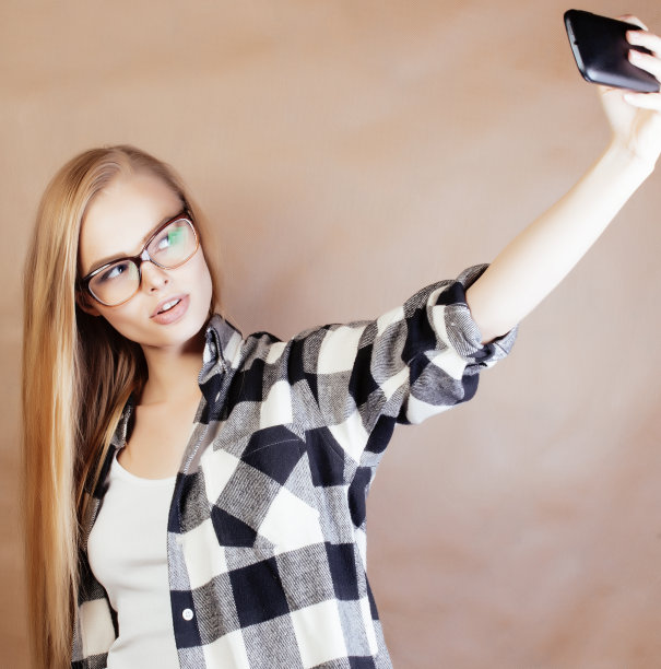 年轻漂亮的女孩十几岁，戴着眼镜在学校自拍，背着背包的学生，生活方式和人的概念图片下载