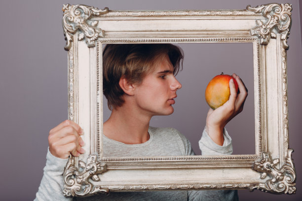 肖像年轻人站在画框在工作室。图片下载