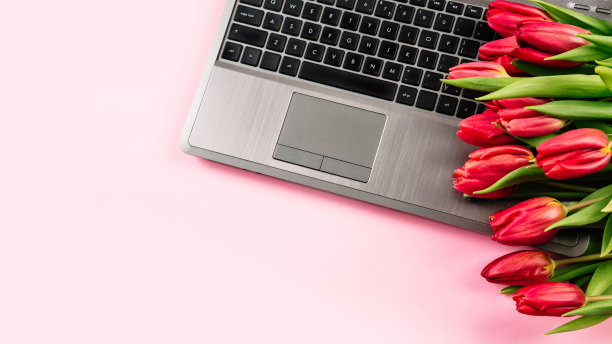 粉红色的办公桌，笔记本电脑和郁金香花束。顶部视图与复制空间。与隔离有关的远程工作和在家学习图片下载