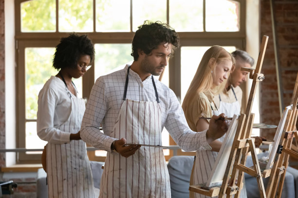 微笑的多种族青年在画布上作画。图片下载