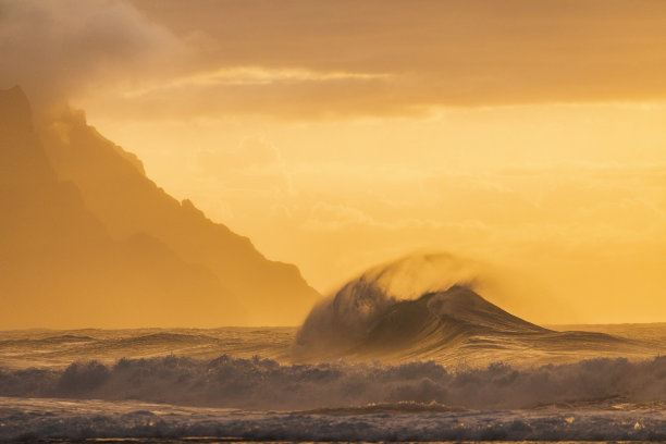 在夏威夷考艾岛金色的夕阳下，巨浪冲击着海岸图片下载