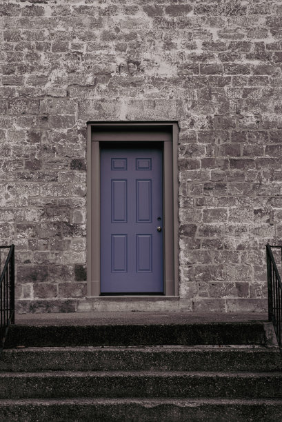 台阶通向一座有着紫色前门的石头建筑。图片下载