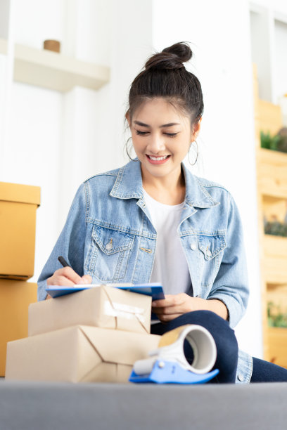 年轻的亚洲休闲妇女工作小型企业在线包装她的支票订单在剪贴板。青少年企业主在家工作。创业小企业主的概念。网上销售，电子商务，航运理念图片下载