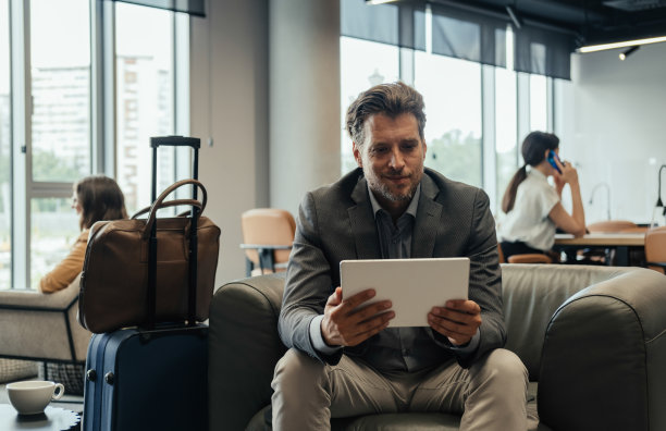 快乐的商人在商务休息室等飞机时使用数码平板电脑图片下载