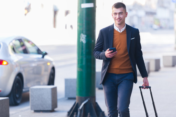 特写照片一个正式的商人拖着他的手提箱，男包，拉包穿过机场(车站)图片下载