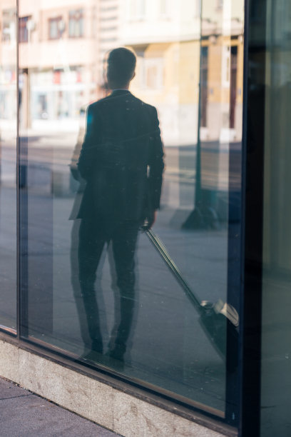特写照片一个正式的商人拖着他的手提箱，男包，拉包穿过机场(车站)图片下载