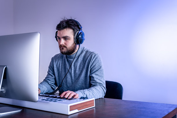 男性音乐家使用电脑和键盘创作音乐，音乐家的工作场所。图片下载