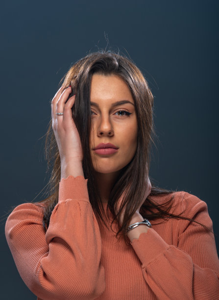 漂亮的年轻女性模特的近距离肖像与黑色背景上的橙色衬衫图片下载