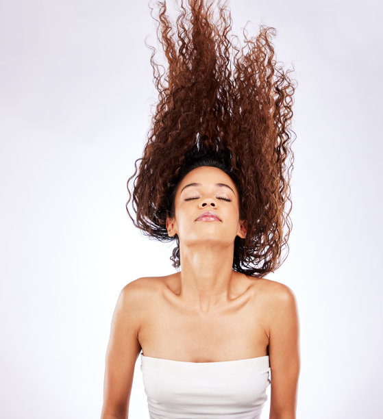 这张照片是一个年轻的女人，在白色的背景下摆出飘逸的卷发图片下载