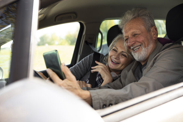 快乐的老年夫妇，车里有智能手机图片下载