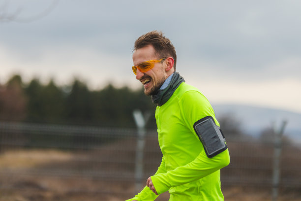 一个年轻男性跑步者的特写穿着充满活力的跑步衣服和跑步太阳镜，在雨天和阴天跑步图片下载