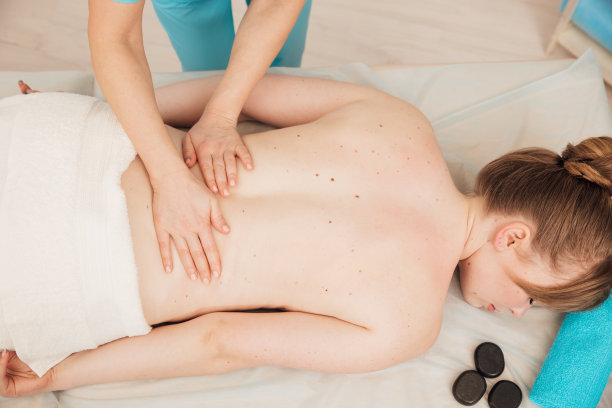 按摩师在水疗中心为妇女进行背部按摩图片下载