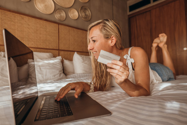 年轻女子在舒适的床上网购-早上好图片下载