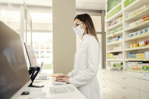 一个年轻的药剂师在药房用电脑工作。图片下载