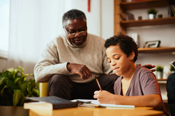 一位非洲爷爷向他的孙子展示如何解决一个数学问题。家庭支持图片下载