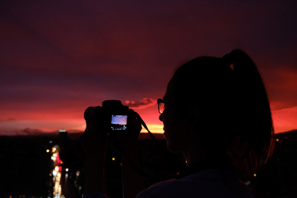 女摄影师剪影拍摄的城市日落照片图片下载