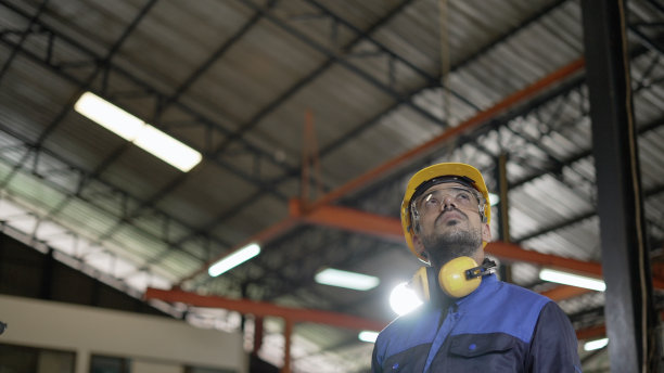 专业工业工程师或技术员的形象有信心，领导和熟练，穿着个人防护装备，站在金属制造工厂的生产线上。图片下载