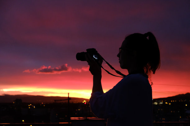 女摄影师剪影拍摄的城市日落照片图片下载