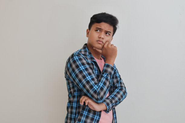 困惑的亚洲男子思考问题，手放在下巴图片下载