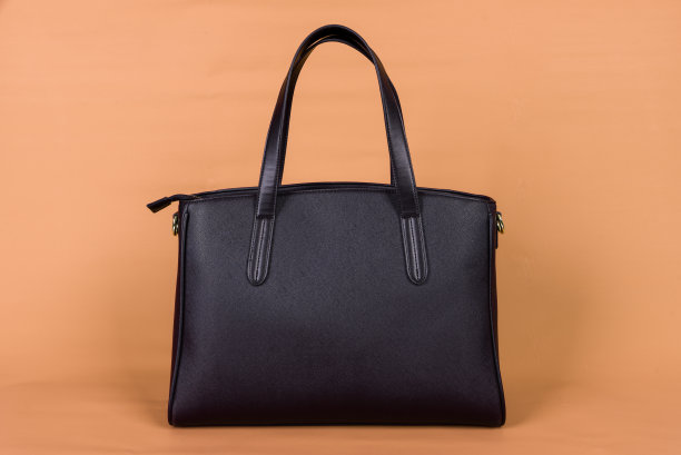 橙色背景的黑色皮包。图片下载