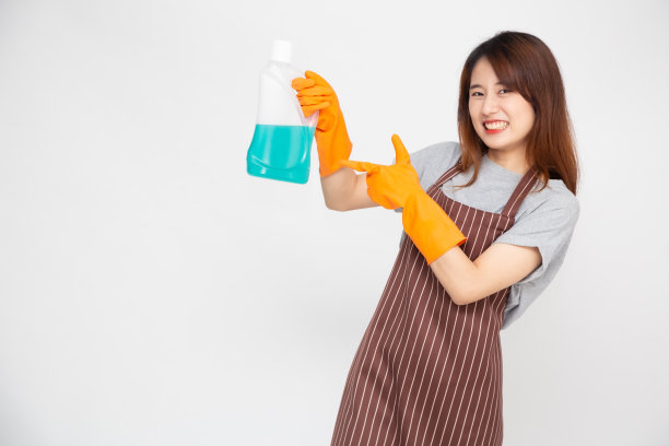 快乐的年轻亚洲女佣或家庭主妇的肖像，戴着橡胶手套，拿着清洁产品孤立在白色背景上图片下载