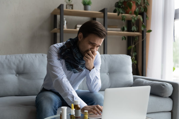 生病的商人打喷嚏，在家里用笔记本电脑工作图片下载
