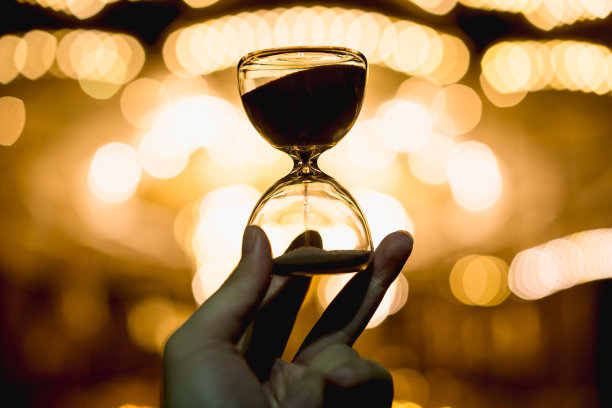 手握金色散景沙漏。现代生活理念，节日与夜晚假期，圣诞节与倒计时。图片下载