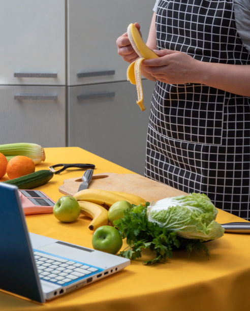 女孩在做奶昔前用手剥香蕉皮。桌子上还有其他的配料和工具。健康饮食。有选择性的重点。图片下载