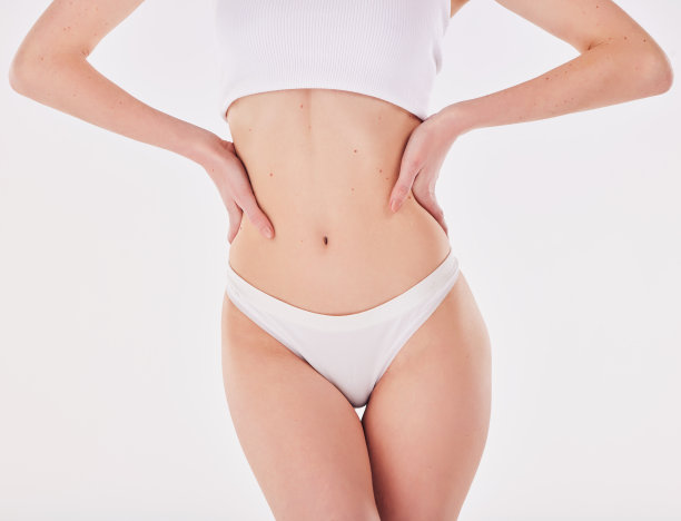 一名女子在摄影棚背景下摆姿势，双手叉腰图片下载