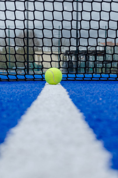 一个蓝色的网球拍和一个球在白线上图片下载