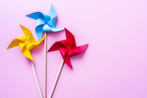 粉红色背景上的彩色风车。本空间图片下载